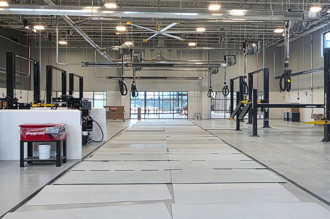 Shop during construction with two-post lifts, overhead exhaust rails and ceiling fans in place
