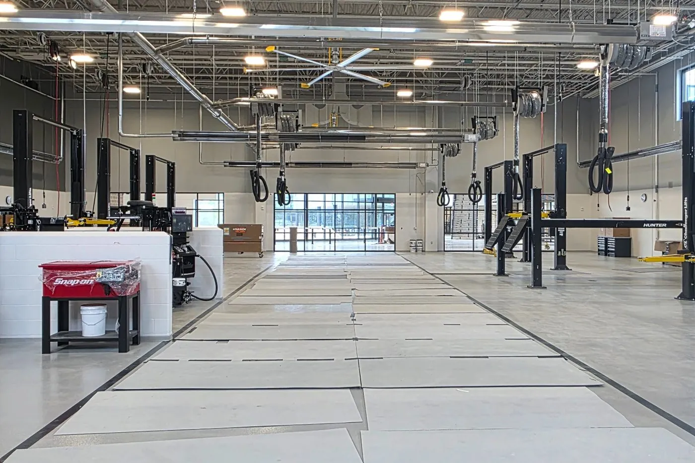 Shop during construction with two-post lifts, overhead exhaust rails and ceiling fans in place