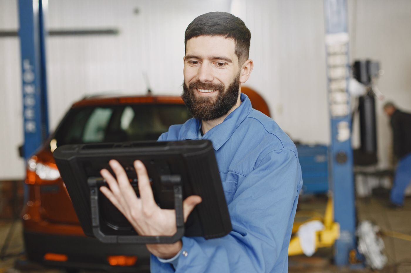 Equipment specialist reviewing shop scope on a tablet in a service bay